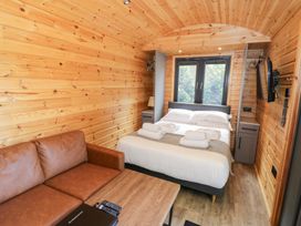 A bedroom with a bed and sofa at The Shepherds Hut at Bridge Lake Farm & Fishery Chacombe