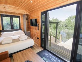 A bedroom with a bed and sliding door at The Shepherds Hut at Bridge Lake Farm & Fishery Chacombe