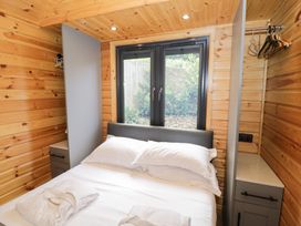 A bedroom with a bed and window at The Shepherds Hut at Bridge Lake Farm & Fishery Chacombe