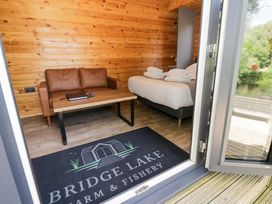 An indoor space with a sofa and a bed at The Shepherds Hut at Bridge Lake Farm & Fishery Chacombe