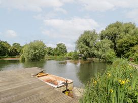 A lake with a boat on a dock at The Shepherds Hut at Bridge Lake Farm & Fishery Chacombe