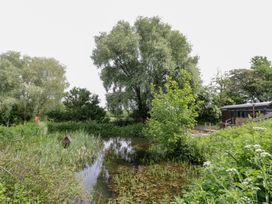 An outdoor area with a pond and surrounding greenery at The Shepherds Hut at Bridge Lake Farm & Fishery Chacombe