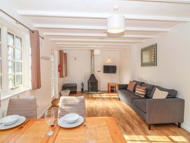 A living room with a sofa and dining area at Bracken Cottage in St Tudy