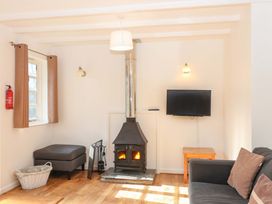 A living room with a fireplace and television at Bracken Cottage in St Tudy