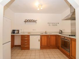 A kitchen with appliances and wooden cabinets at Bracken Cottage in St Tudy