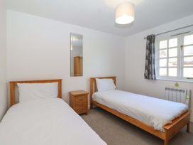 A bedroom with two beds and a nightstand at Bracken Cottage St Tudy