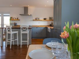 A kitchen with bar stools and shelves at 38 Venn Park Stoke Fleming