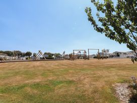 An outdoor playground with swings and climbing frame at 97 Crugan Llanbedrog