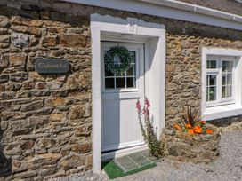 An entrance of a stone cottage with a door and planter at Cobwebs Cold Inn near Saundersfoot