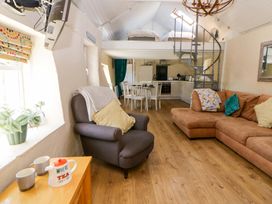 A living room with a sofa and dining area at Cobwebs Cold Inn near Saundersfoot