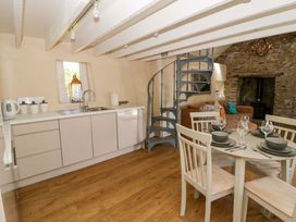 A kitchen with a dining table and spiral staircase at Cobwebs Cold Inn near Saundersfoot