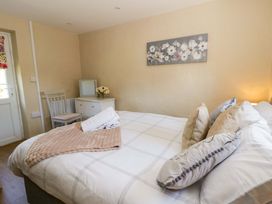 A bedroom with a bed and a chair at Cobwebs in Cold Inn near Saundersfoot