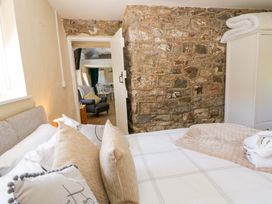 A bedroom with a bed and stone wall at Cobwebs Cold Inn near Saundersfoot