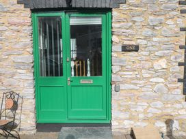 A green door with glass panels and a black sign saying one on a stone wall at 1 Greenswood Court in Brixham