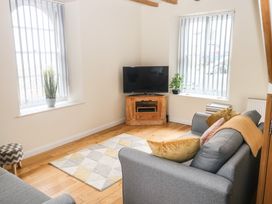A living room with sofas cushions rug television and plants at 1 Greenswood Court in Brixham