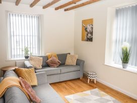A living room with two gray sofas and cushions a small table and plants with beams on the ceiling at 1 Greenswood Court in Brixham