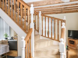 A staircase with wooden banisters and carpeted steps in a living area with a dining table and a television at 1 Greenswood Court in Brixham