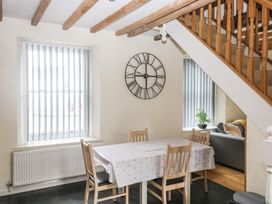 A dining area with a table and four chairs under wooden ceiling beams and a staircase at 1 Greenswood Court in Brixham