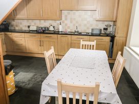 A kitchen with wooden cabinets a table with a white cloth and four chairs at 1 Greenswood Court in Brixham