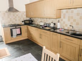 A kitchen with wooden cabinets a black countertop a stove a microwave a toaster a kettle and a sink at 1 Greenswood Court in Brixham