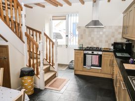 A kitchen with wooden stairs a gas stove oven with towels a microwave and a door leading outside at 1 Greenswood Court in Brixham