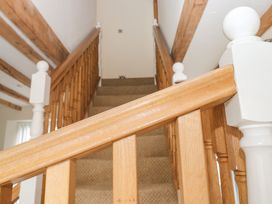 A carpeted staircase with wooden banisters and white newel posts in a house with exposed wooden ceiling beams at 1 Greenswood Court in Brixham