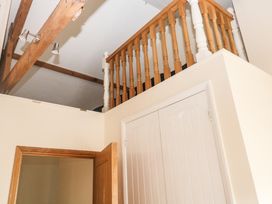 Ceiling with wooden beams and spotlights a wooden railing and white doors in a hallway at 1 Greenswood Court Brixham
