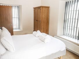 A bedroom with a bed with white linens two rolled towels on the bed a wooden wardrobe a radiator and windows with vertical blinds at 1 Greenswood Court in Brixham