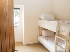 A small bedroom with a white bunk bed and a door to the outside at 1 Greenswood Court in Brixham
