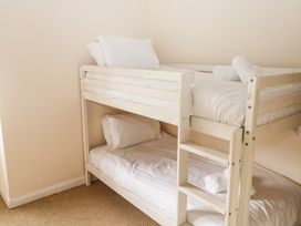 A bunk bed with white bedding and rolled towels on a carpeted floor at 1 Greenswood Court in Brixham