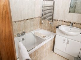 A bathroom with a bathtub a towel rail a sink cabinet and tiled walls at 1 Greenswood Court Brixham