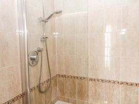 A shower area with beige tiles a handheld showerhead and control knobs at 1 Greenswood Court in Brixham