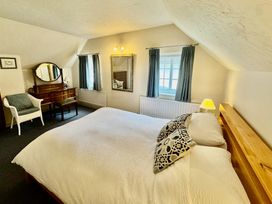 A bedroom with a bed, dressing table and window at Cajun Cottage in West Lulworth