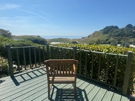 A chair on a deck overlooking the ocean at Cajun Cottage in West Lulworth