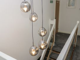 A hallway with hanging light fixtures and a staircase at Eildon Lodge in Gosforth