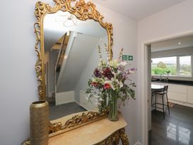 A hallway with a mirror and flowers at Eildon Lodge in Gosforth