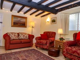 A living room with a sofa, chairs, and lamp at Fox Hat Cottage in Chagford