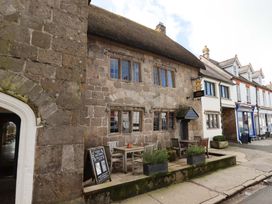 A stone building with tables and chairs outside at Fox Hat Cottage in Chagford