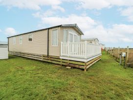 A mobile home with a deck in an outdoor area at Trewan Chalet Bryngwran near Rhosneigr