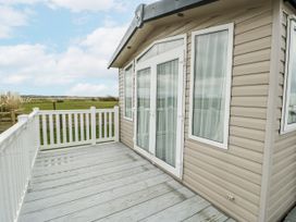 An outdoor area with a cabin and decking at Trewan Chalet Bryngwran near Rhosneigr