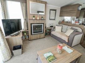 A living room with a fireplace and television at Trewan Chalet Bryngwran near Rhosneigr