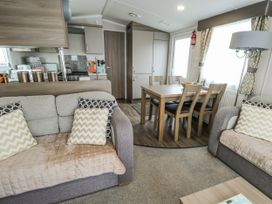 A living room with a dining table and chairs at Trewan Chalet Bryngwran near Rhosneigr