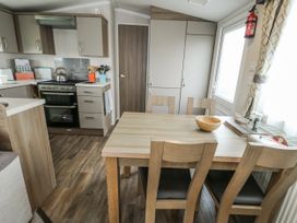 A kitchen with a dining table and chairs at Trewan Chalet in Bryngwran near Rhosneigr