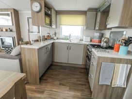 A kitchen with cabinets, stove, and sink at Trewan Chalet in Bryngwran near Rhosneigr
