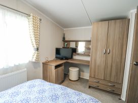 A bedroom with a bed and a desk at Trewan Chalet Bryngwran near Rhosneigr