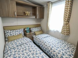 A bedroom with two single beds and a shelf at Trewan Chalet Bryngwran near Rhosneigr