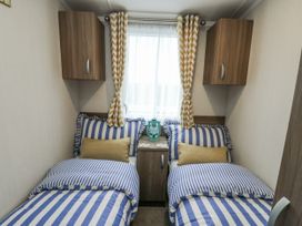 A bedroom with twin beds and a nightstand at Trewan Chalet in Bryngwran near Rhosneigr