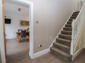 A hallway with a staircase and a view into the dining area at Chestnuts Cottage in Windermere
