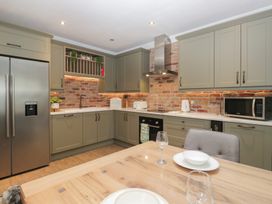 A kitchen with appliances and dining table at Chestnuts Cottage in Windermere