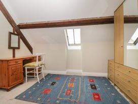 An attic room with a wooden desk and chair mirror skylight and a wardrobe with drawers at The Old Haberdashery in Swanage